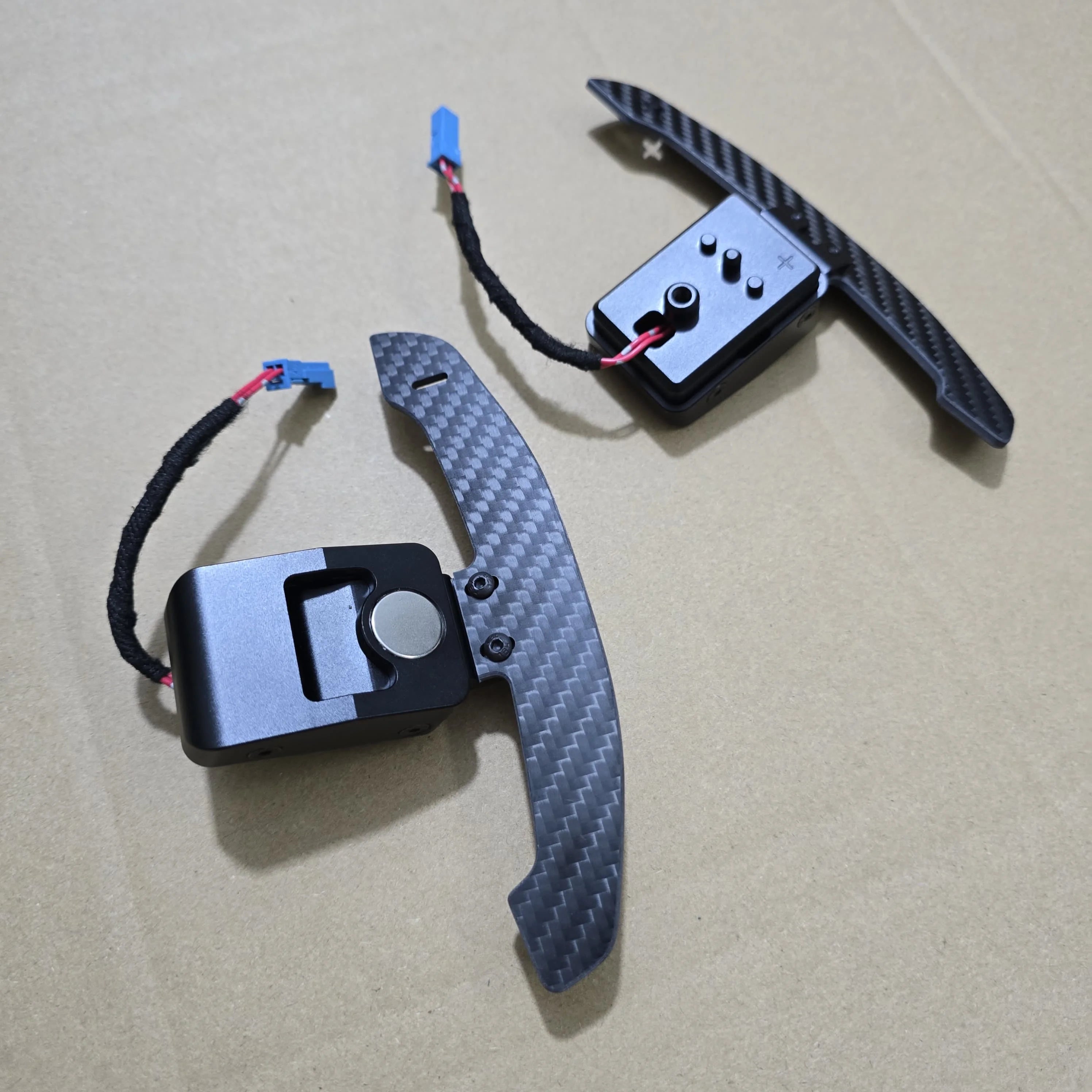 Carbon fiber and metal components on a beige surface